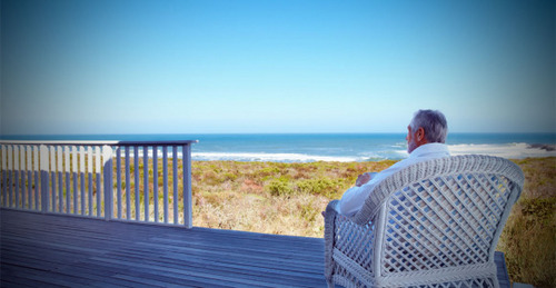 Rear view of a mature man relaxing on a chair while facing outdo Rear view of a mature man relaxing on a chair while facing outdo