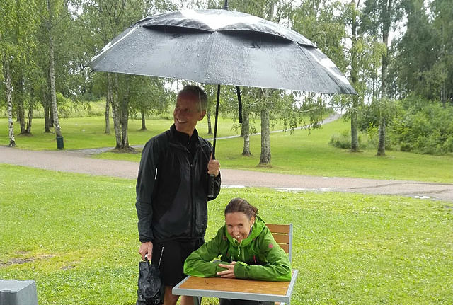 Klara Lyngnes passer godt på PCen i regnevære, mens SRM-venn Per Magnus Holt hjelper til med paraplyen.