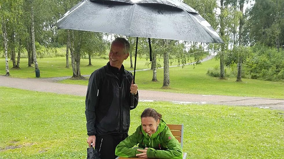 Klara Lyngnes passer godt på PCen i regnevære, mens SRM-venn Per Magnus Holt hjelper til med paraplyen.