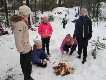 Jentene steker pølse på bålet.