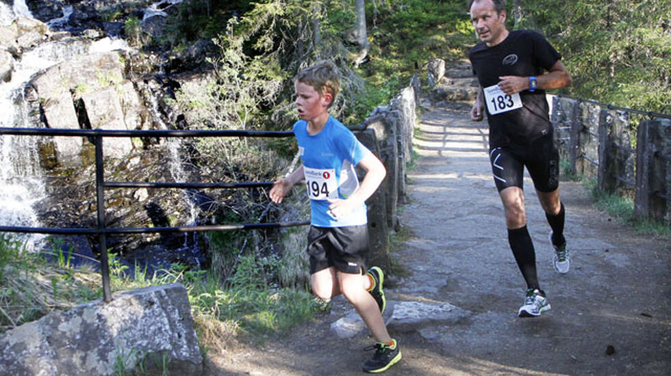 To av deltakerne, Ola Drageset-Haug (194) i klasse M 0-15 år, og Arve Hilleren (183) i klasse M 50-59 år krysser Mesnaelva over Collets bru. Langs med Mesna finner vi rester av historiske bygninger og aktiviteter langs hele strekningen fra elveoset ved Strandtorget og opp til Collet bru, som er oppkalt etter maleren Frederik Collet. Han ble så betatt av lysspillet over Mesna at han de siste 30 år av sitt liv ikke malte stort annet. Foto: Jørgen Skaug