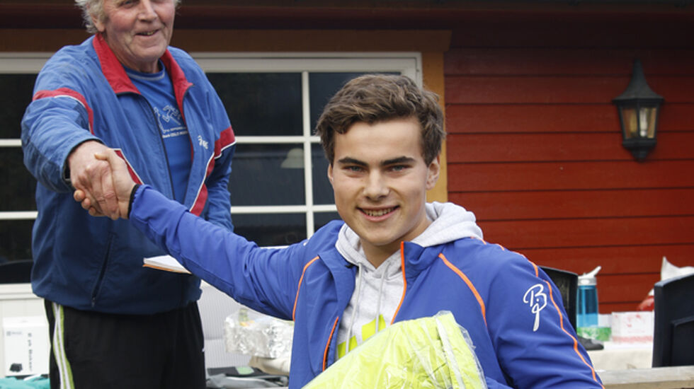 Vegard Øvrevik  blir gratulert med seieren av Arne Moren i Strandvoldbruas venner som nå har fått inn godt over en million kroner til bruprosjektet i nabolaget. 