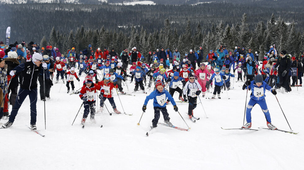Simen Andreas Sveen heiet i gang 5-7-åringene opp Monsterbakken med Martin Johnsrud Sundby i bakgrunnen.