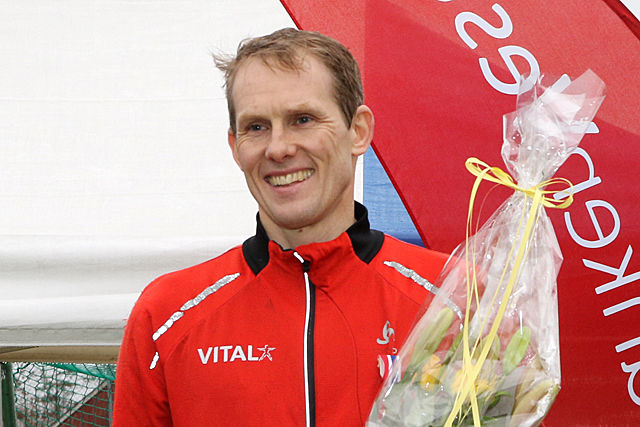 Svein Glomnes mottar premie og blomster etter å ha løpt inn til seier i NM terrengløp for veteraner.
