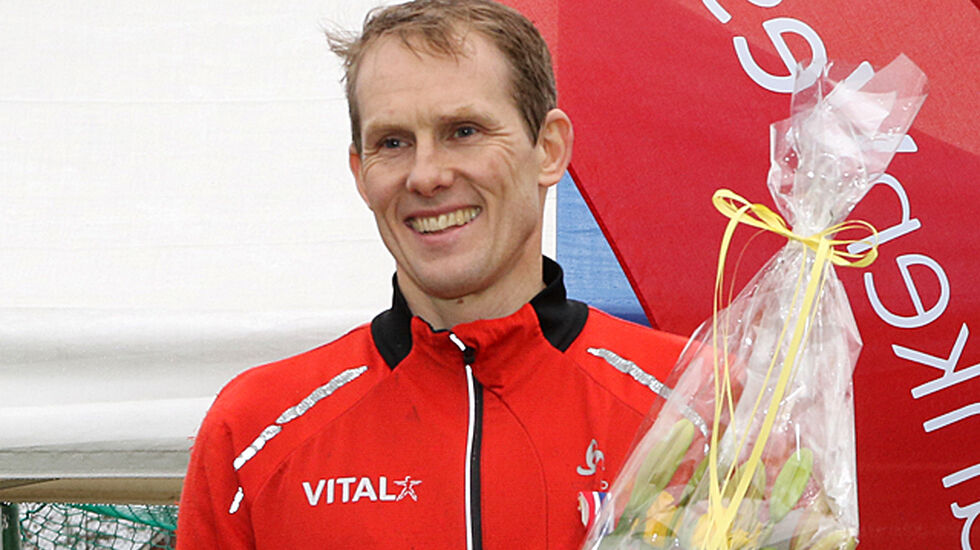 Svein Glomnes mottar premie og blomster etter å ha løpt inn til seier i NM terrengløp for veteraner.
