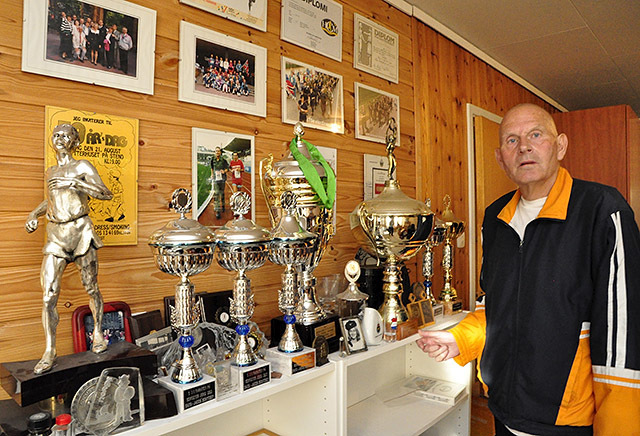 Hans Jakob Berntsen var ikke redd for å utfordre seg selv, og pokalsamlinga forteller om noe av det han var med på. De to største pokalene er for 200 helmaratonløp og for Jernmannstatuetten 10 ganger. (Foto: Trygve Hillestad)