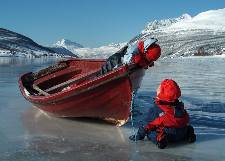 Barn og båt i vinterlandskap på fjorden