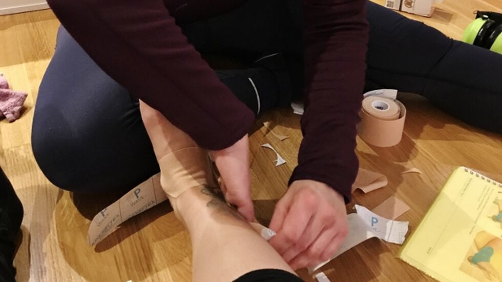 Marthe setter på kinesiotape på den vonde ankelen