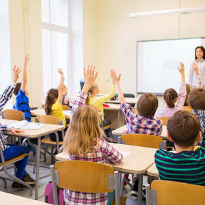 Bilde av skoleelever som rekker hånda i været