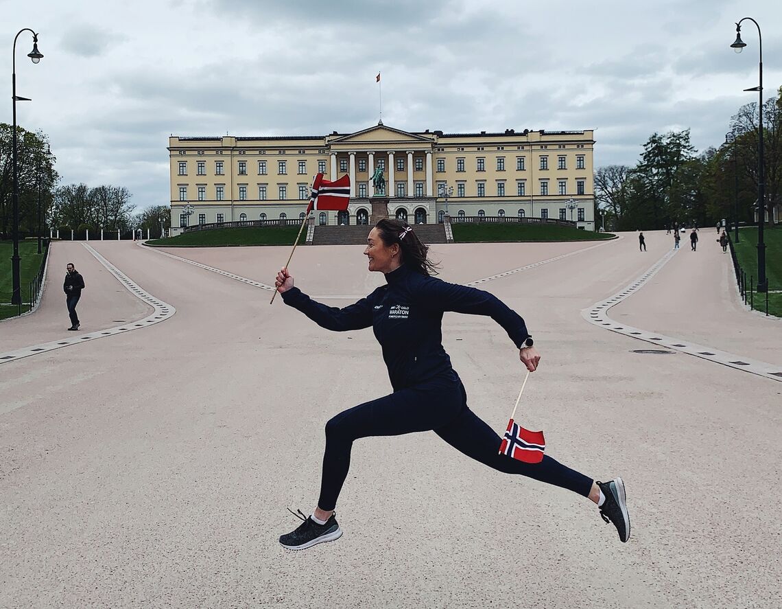 Oslo Maraton-ansatte Emilie Kjustad Hauer i luftig 17. mai-sprang foran slottet. (Foto: Oslo Maraton) 