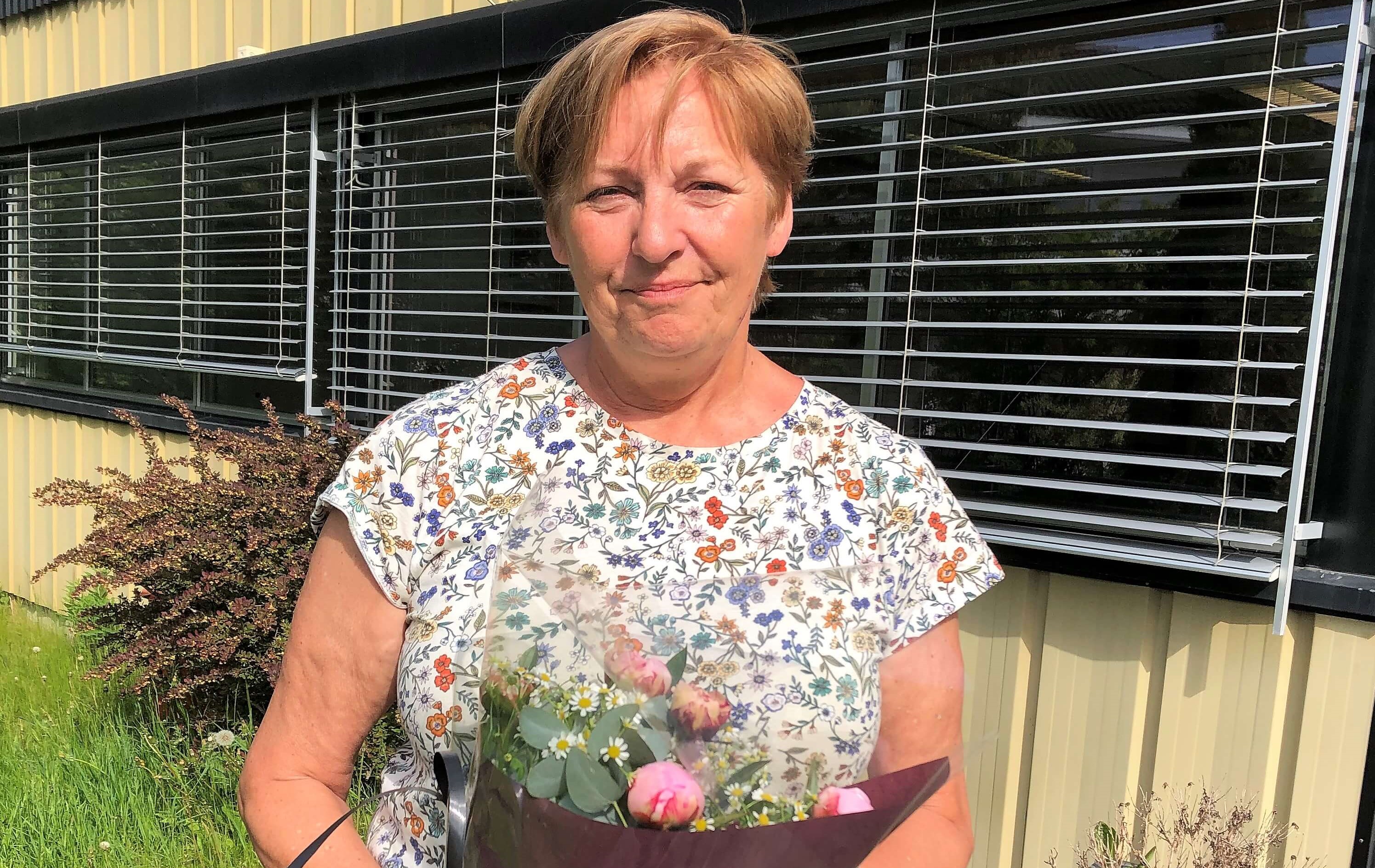 Bilde av Ida Husby fra Helsport, som klippet stoffet til smittefrakkene. Hun fikk blomster som takk for innsatsen. 