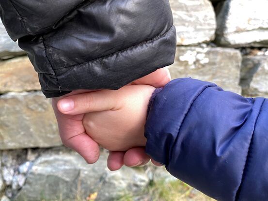 Vaksen og barn som held kvarandre i hendene