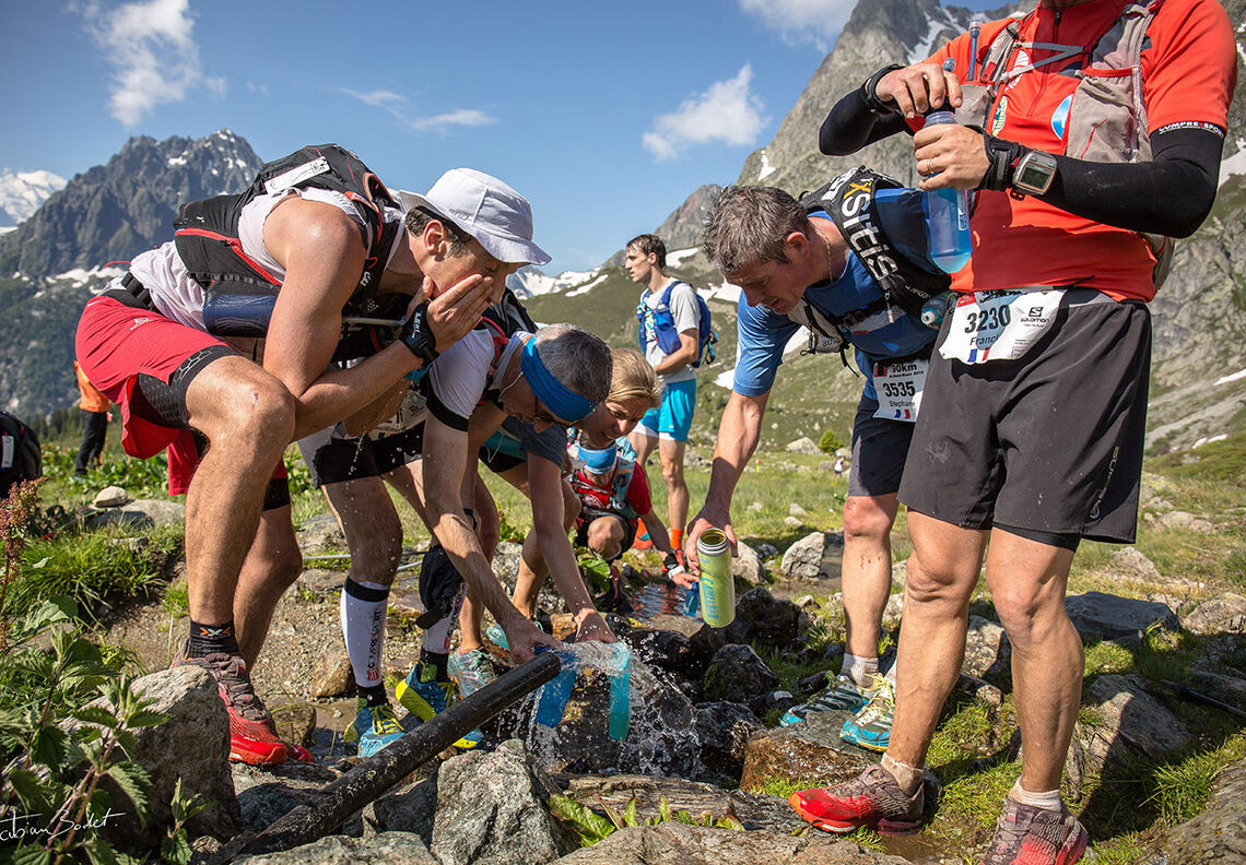 Løpere i Ultratrail du Mont Blanc fyller opp både kropper og drikkeflasker. (Foto: UTMB / Fabian Bodet)