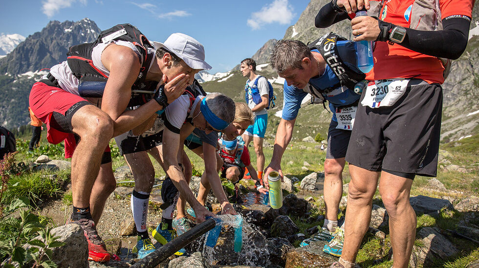 Løpere i Ultratrail du Mont Blanc fyller opp både kropper og drikkeflasker. (Foto: UTMB / Fabian Bodet)