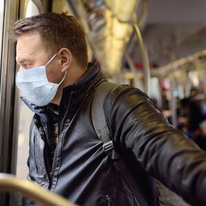 Illustrasjonsbilde av en mann som bruker munnbind på bussen