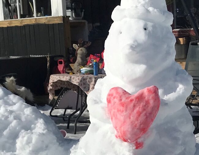 Snømann som holder rødfarget hjerte av snø