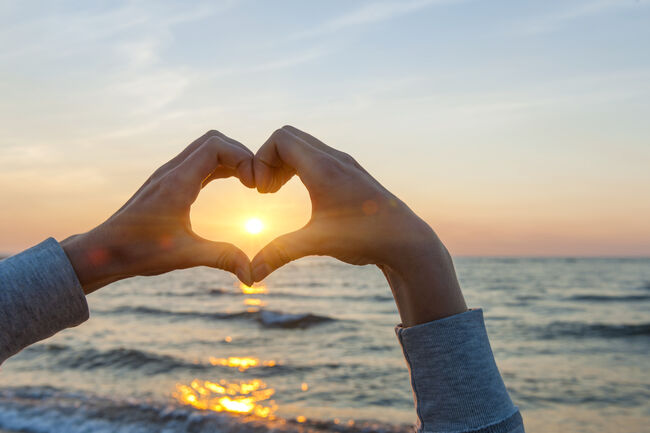 Bilde av hjerteformede hender sol og hav