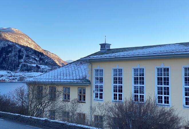 Tinghuset på Leikanger sett mot Hermansverk med sol på snødekte toppar.