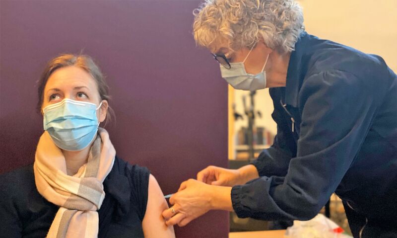 Bilde av helsesykepleier Laila Reitan Sundet som setter vaksine på sykepleier June Vehn Jensvold, som jobber på Buen helse- omsorgssenter. Denne dagen hjalp hun også til med vaksineringen på Melhus bedehus.