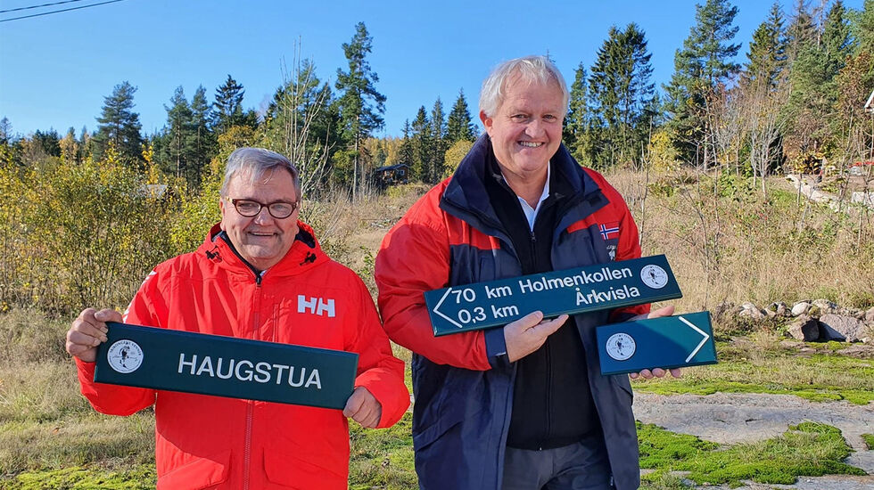 Ildsjelene Knut Olaf Kals (til venstre) og Marius Morin viser fram noen av skiltene som skal guide både fotturister og ultraløpere fra Lier til Holmenkollen. (Foto: Gjermund Sørstad)