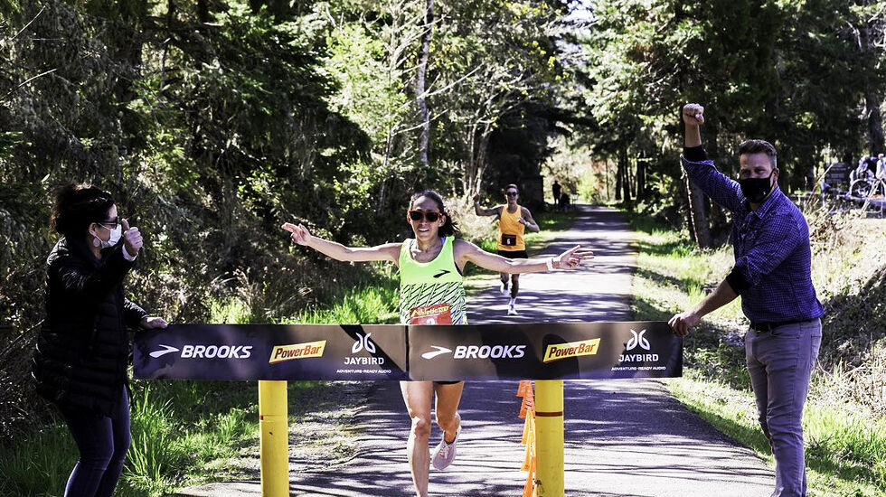 Fartsholder Charlie Lawrence har sluppet henne fram, og Des Linden krysser målstreken som vinner på ny bestetid i verden på 50 km. (Foto: Brooks Running)