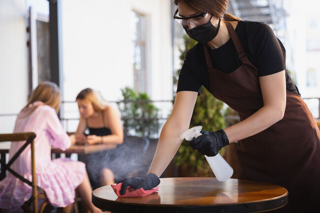 The waitress works in a restaurant in a medical mask, gloves during coronavirus pandemic