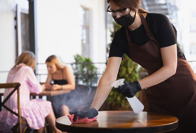 The waitress works in a restaurant in a medical mask, gloves during coronavirus pandemic