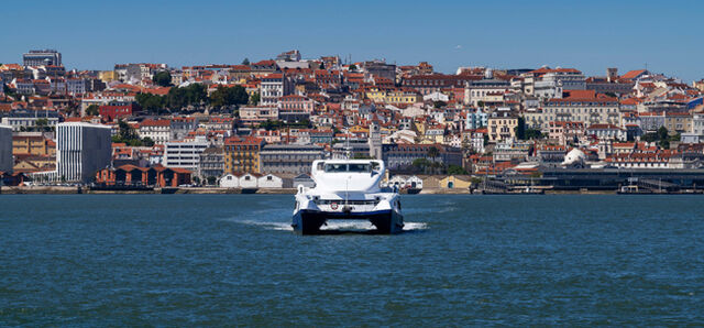 A ferry boat crossing the Tagus River (Rio Tejo) with the city of Lisbon skyline on the background, in Portugal
