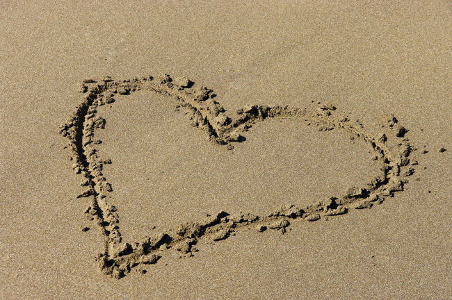 a heart is drawn in the sand on the beach