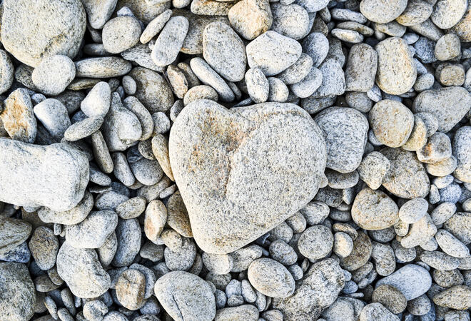 A heart-shaped stone on a pebble beach in France.