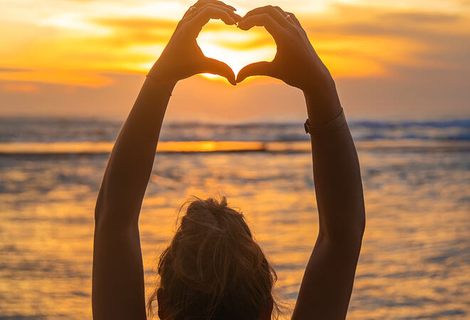 Girl makes heart hands at sunset. Sri Lanka. Selective focus.