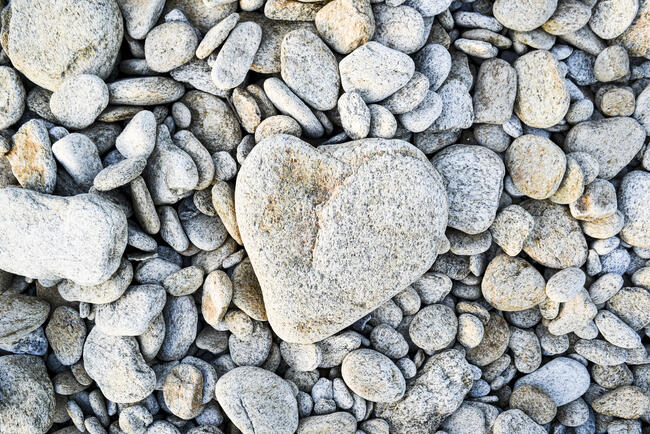 A heart-shaped stone on a pebble beach in France.