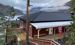 Brunt bygg med flagg, utsyn over fjord og fjell.