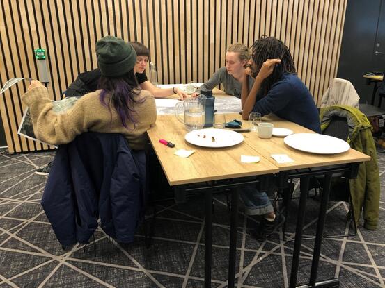 Fire studentar sit rundt ein bord og teiknar.