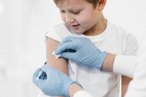 Barn vaksineres av helsepersonell.