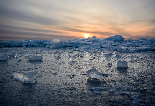 Abstract frozen winter sunrise seascape with ice and colored the