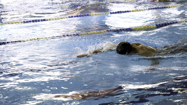 Man Swimming in Pool. Fit young male swimmer training in the pool. Young man swimming the front crawl in a pool. Young male athlete swimming freestyle in pool during competition
