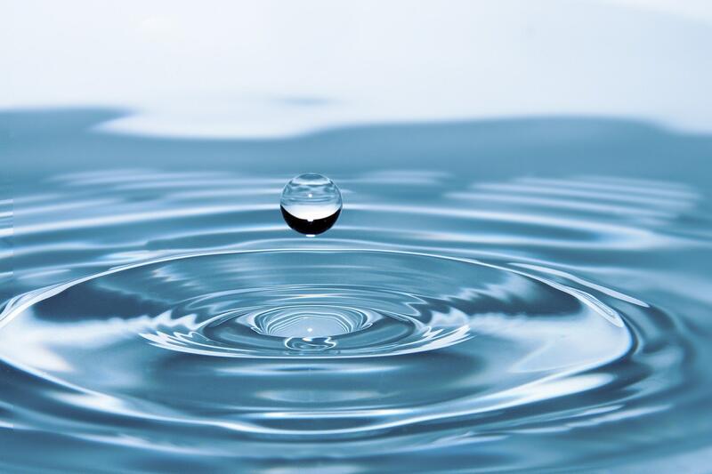 En vanndråpe faller ned mot et blått vann.