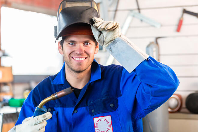 Welder with welding device in metal workshop