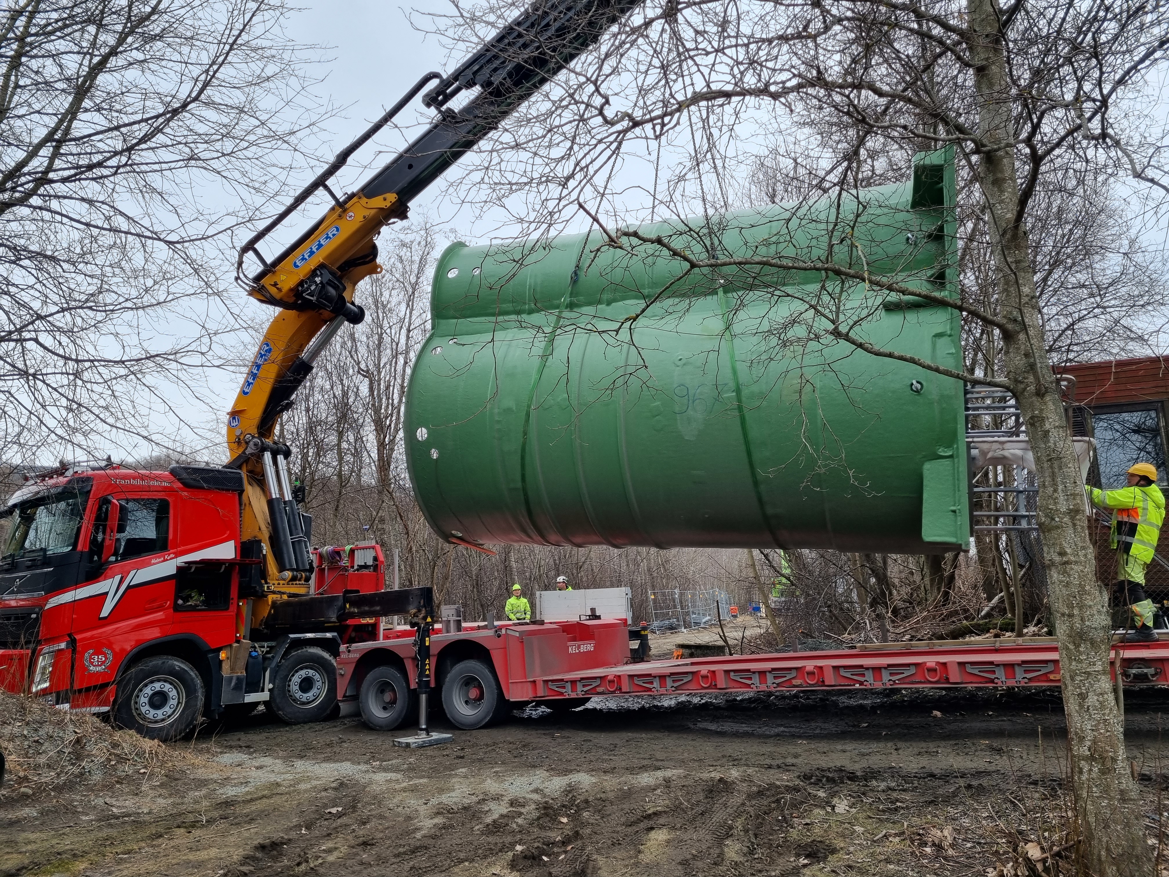En tank til avløpspumpestasjon blir tatt av en trailer.
