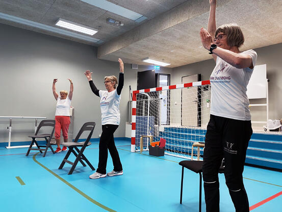 Instruktører og deltakere strekker seg opp mot taket