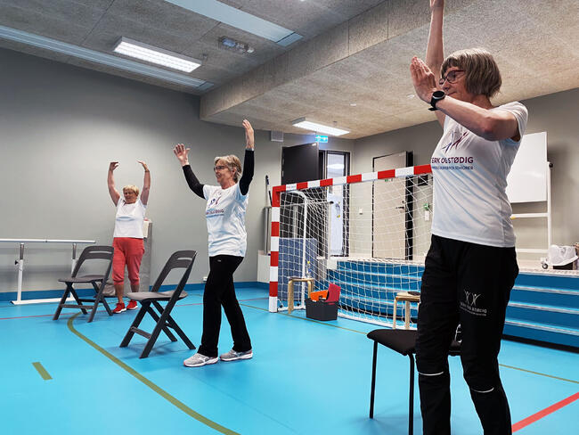 Instruktører og deltakere strekker seg opp mot taket