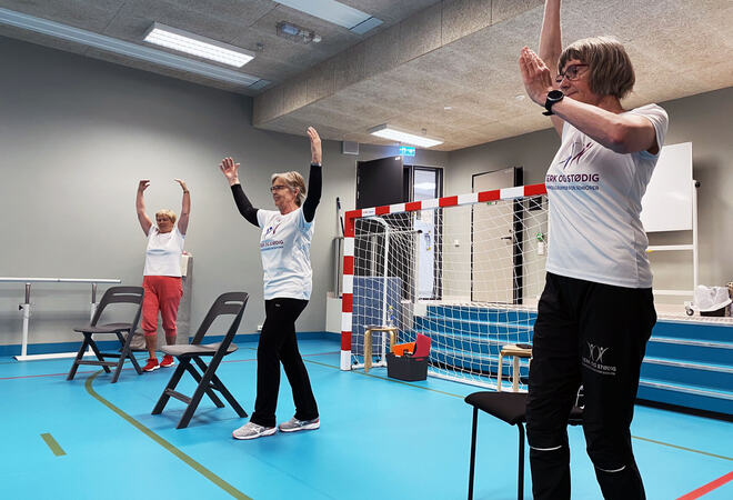 Instruktører og deltakere strekker seg opp mot taket