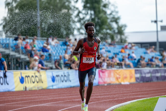 Zerei Mezngi løper gjennom dusjen som skulle hjelpe 10000 m-løperne gjennom 25 runder i heten. (Foto: Samuel Hafsahl)