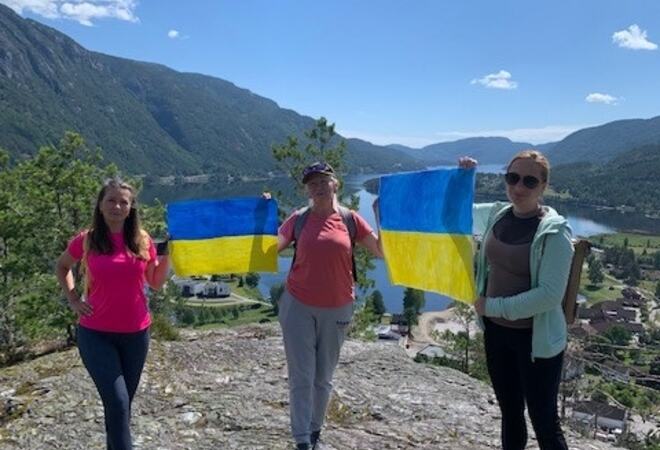 Tre menneske som held ukrainske flagg mellom seg, mens dei står på toppen av Bringsåsnuten