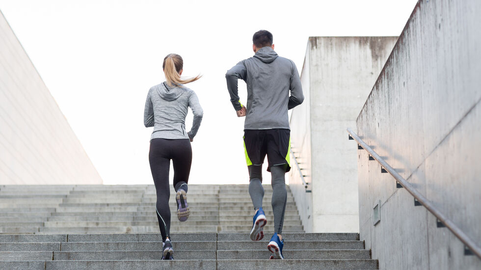 fitness, sport, people, exercising and lifestyle concept - couple running upstairs on city stairs