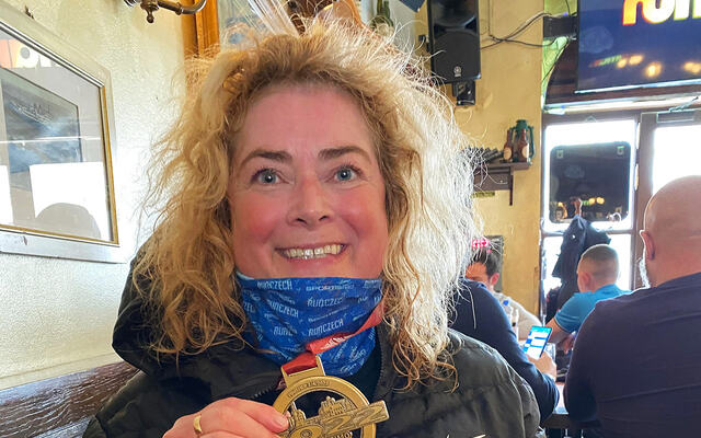 Marianne Telle med medaljen hun fikk etter sin halvmaraton nummer seks i Praha, byen som er hennes favorittsted å løpe. (Foto: privat)