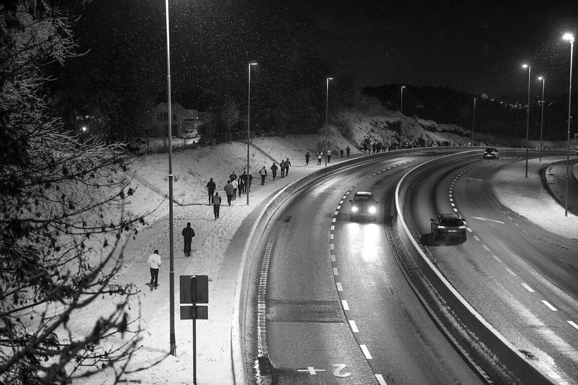 Løperne beveger seg oppover Flyplassveien på snødekke og med lette snøfnugg i luften. (Alle foto: Arne Dag Myking)