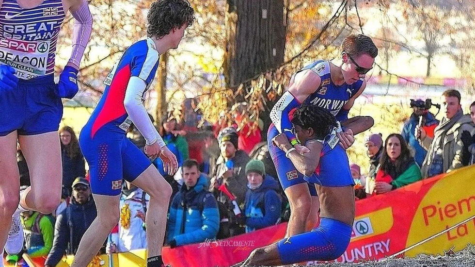 Esten Hansen-Møllerud Hauen (til venstre) og Vebjørn Hovdejord stansa for å hjelpe Abdullahi Dahir Rabi under EM terrengløp. (Foto: Atl-Eticamente foto)