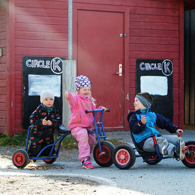 Barn sykler på utsiden av barnehagen